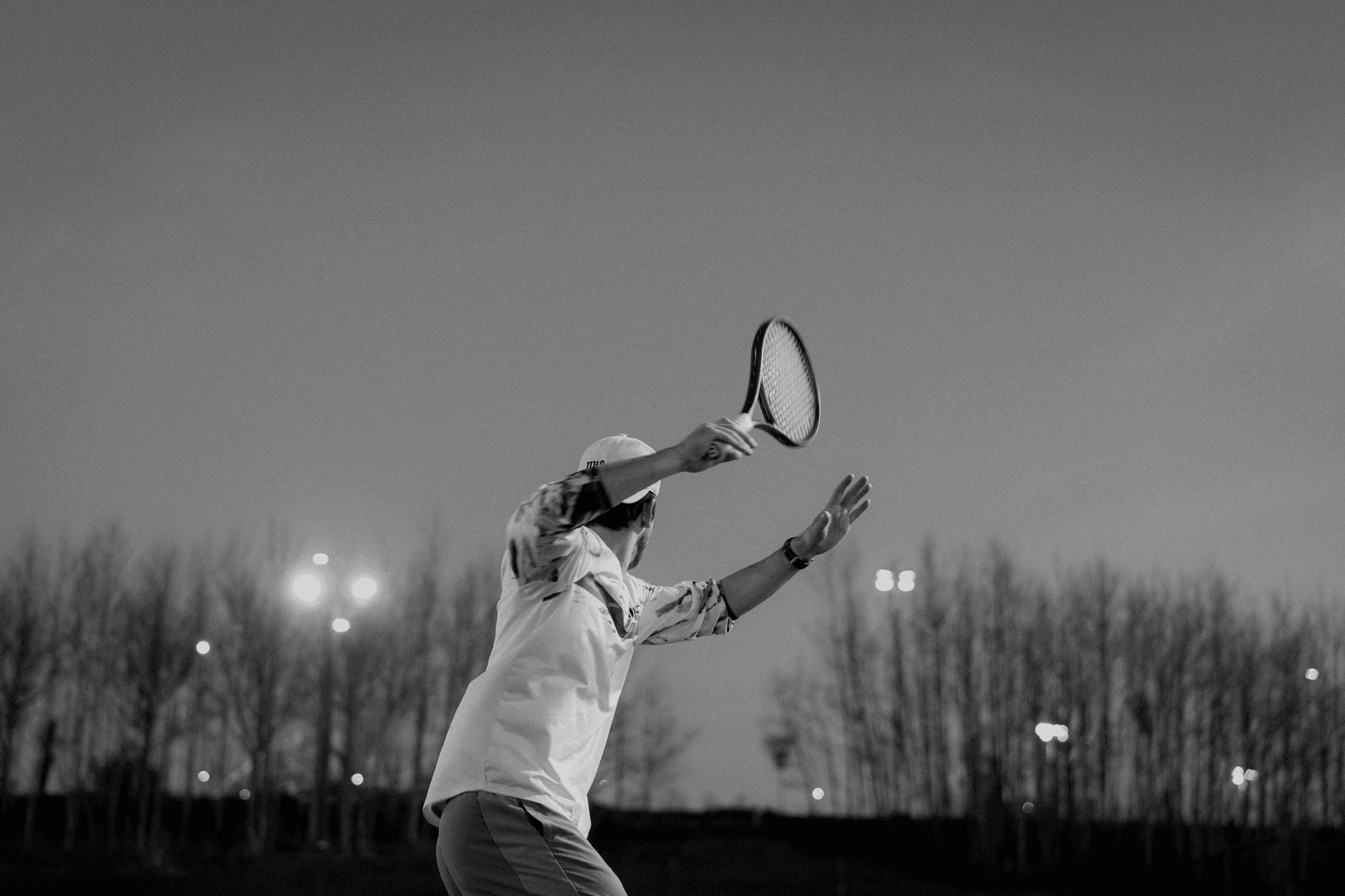 Tennis player preparing a shot on court under evening lights