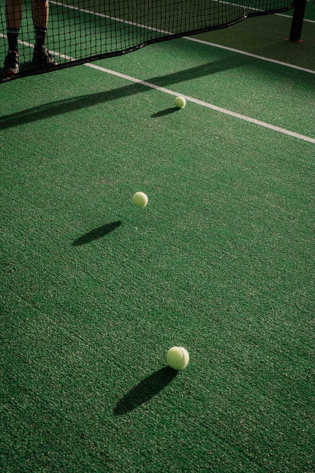 Three tennis balls on a green court beside the net