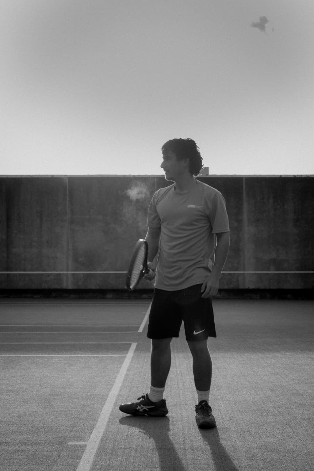 Tennis player standing on court with racquet in black and white